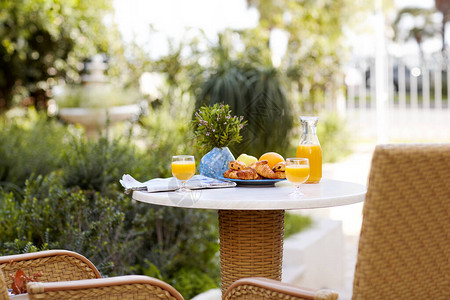 餐桌上的早餐包括新鲜的松饼羊角面包水果和鲜榨橙汁图片
