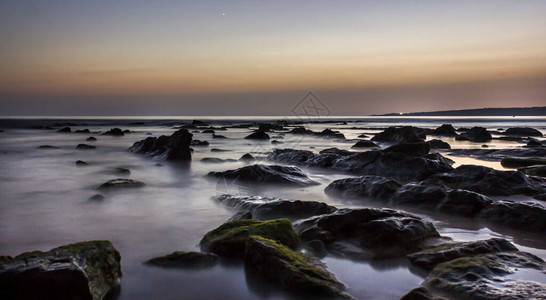 日落时有岩石的海滩景观图片