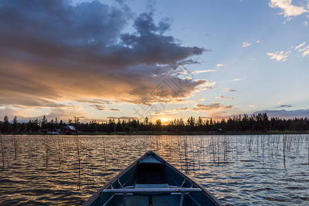 日落时湖上蓝色独木舟船头的特写图片