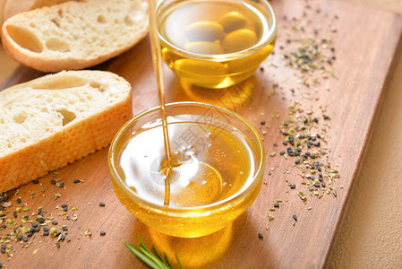 将美味的橄榄油倒入桌子上的碗中图片