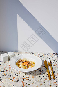 在阳光下石桌上的美味意大利面配上金色餐具盐和胡椒瓶图片