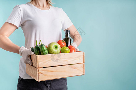 Corona食品供应身戴手套的妇女拿着一个木箱装满蔬菜的木箱图片