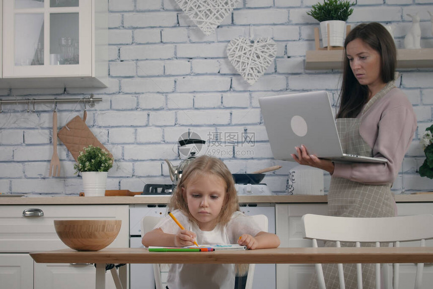 母亲和她5岁的女儿在厨房进行自我隔离以防隔离穿着围裙的女人在做饭时用笔记本电脑工作图片