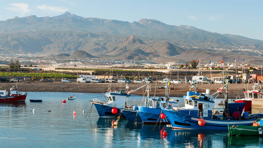 在山坡海岸和Teide火山峰背景的码头对停靠在岸边的浮游渔船图片