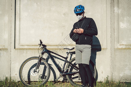 骑自行车的戴着防护口罩的快递员停下来图片