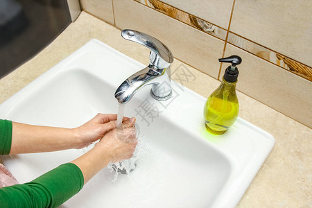 带肥皂的手在水龙头下用水清洗清除感染污垢和在家中图片