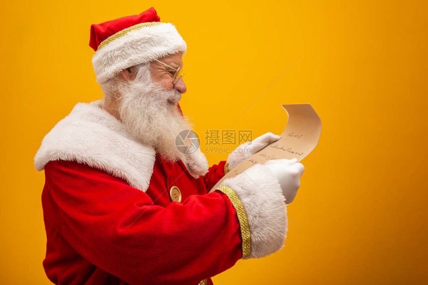 快乐的圣诞老人拿着黄色背景的老式纸圣诞快乐和新年前夜的概念复制空间阅读困难图片