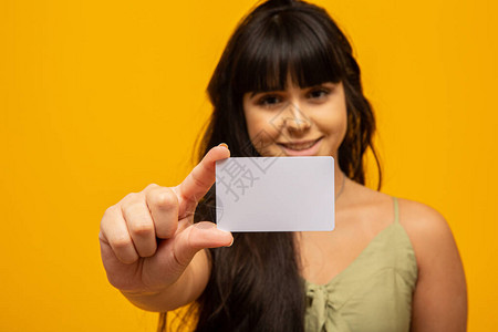 年轻女子手持带圆角的空白卡样机普通电话卡模拟板握臂塑料信用卡名片展示正面检查偏移卡设背景图片
