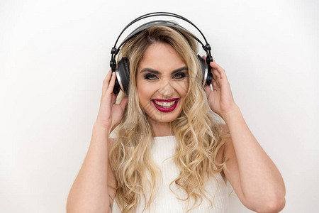 一位年轻女歌手的耳机肖像聆听音乐歌唱以快乐的表图片