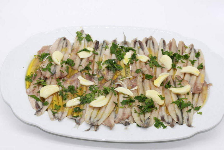 白盘上用橄榄油大蒜和醋腌制的凤尾鱼图片