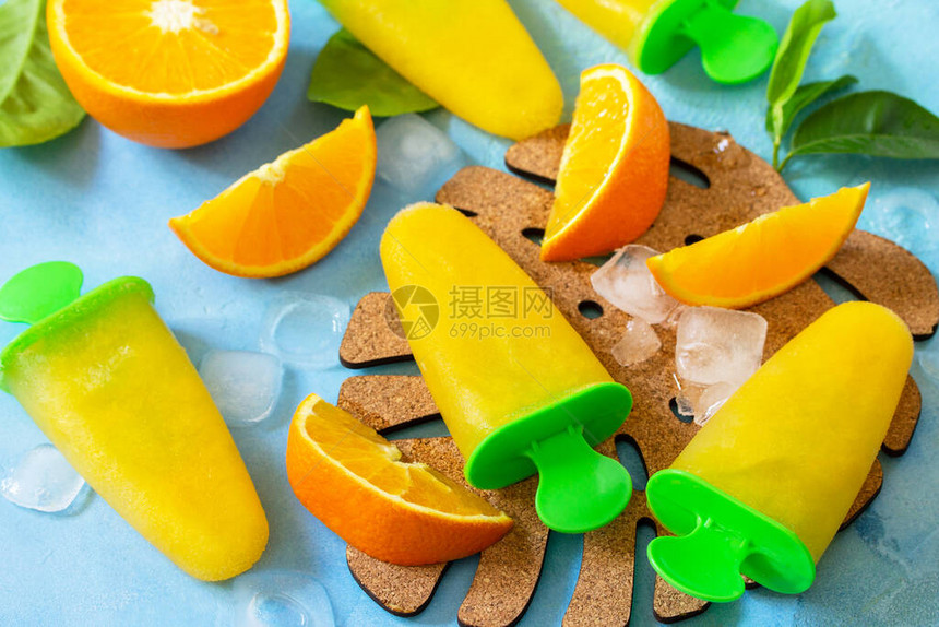 有橙汁水果冰蓝石头上的棒糖或石板背图片