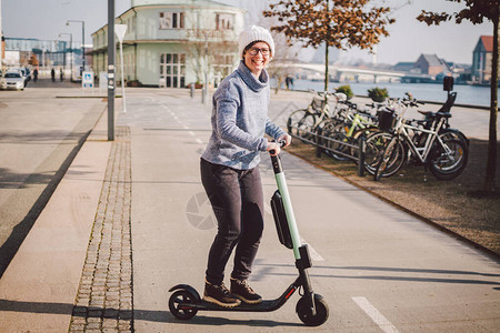 旅游妇女在丹麦首都哥本哈根租用电动滑板车图片