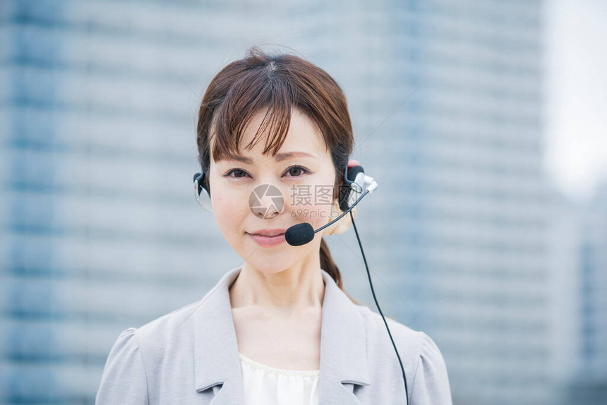 亚洲日语女经营者在商业区戴带麦克风的耳机图片