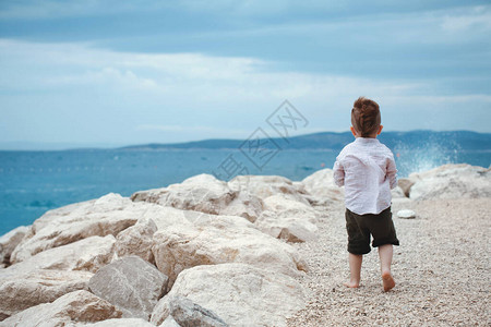 小男孩背对着海边站着图片