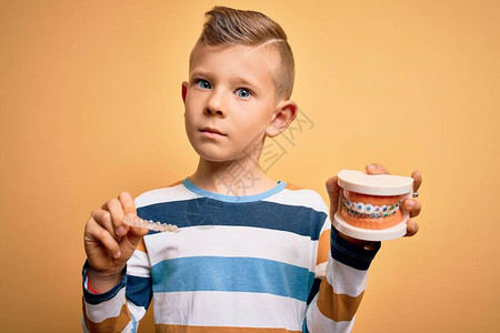 小男孩拿着带金属牙套和可拆卸隐形矫正器的专业正畸假牙两种牙齿矫图片