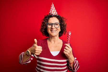 中年卷发女人戴着生日风趣帽举行派对小号庆祝图片