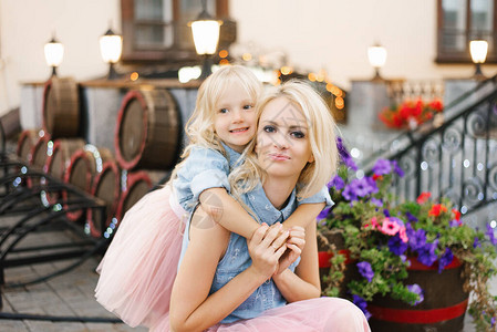 金发碧眼的妈和小女儿穿着粉红色的裙子和牛仔衬衫女儿拥抱她的母亲快乐图片