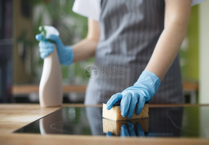 无法辨认的妇女用消毒喷雾模糊背景的手套在厨房打扫清洁图片