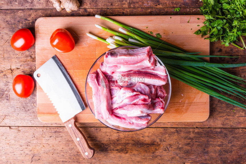 在玻璃碗西红柿香料和木制切割板上的肉小斧子中原切碎的猪排图片