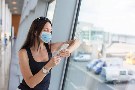 戴面罩以防止在国际机场携带行李的感染的妇女图片