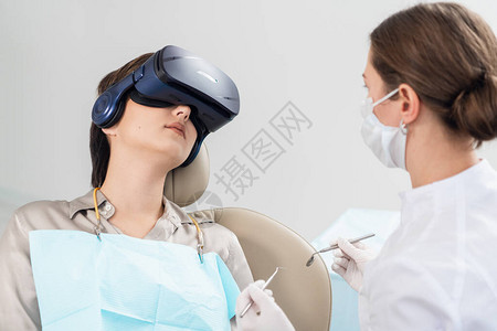 牙医在牙科椅上检查病人的牙齿图片