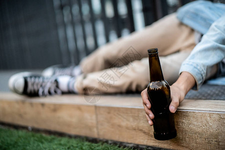 失业的亚洲年轻人带着啤酒瓶独自坐在路边图片