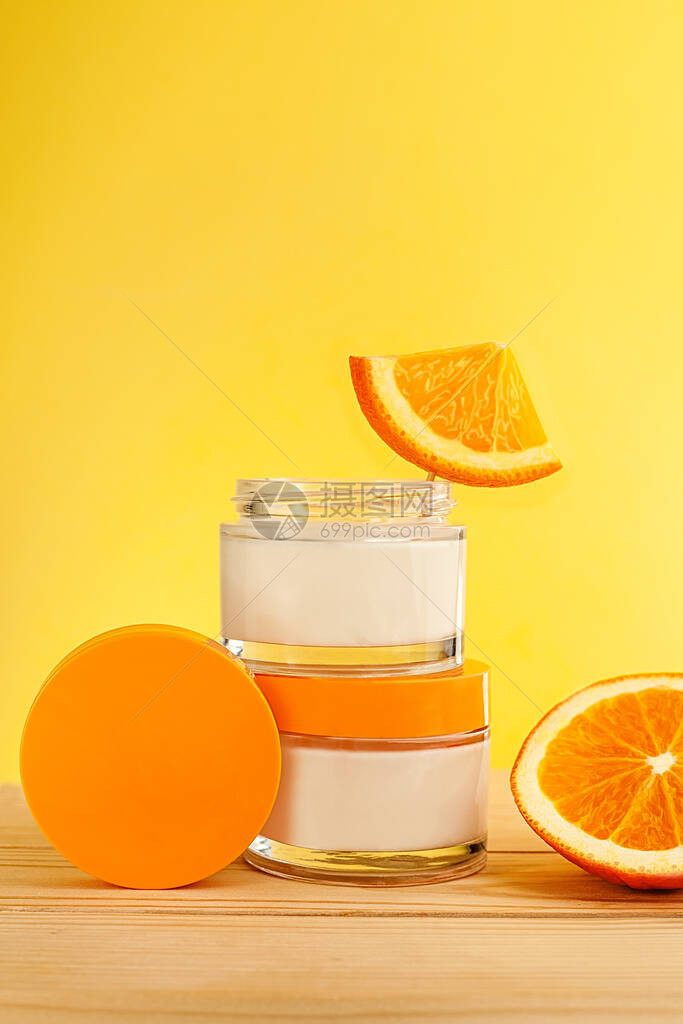 配有天然维生素的维他命护理木制桌子和黄色背景上含橙子的化妆品组装图片