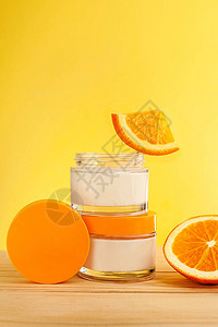配有天然维生素的维他命护理木制桌子和黄色背景上含橙子的化妆品组装图片