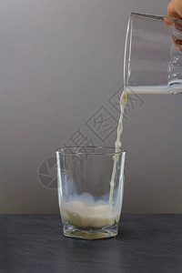 牛奶倒入石桌上的小玻璃杯中图片