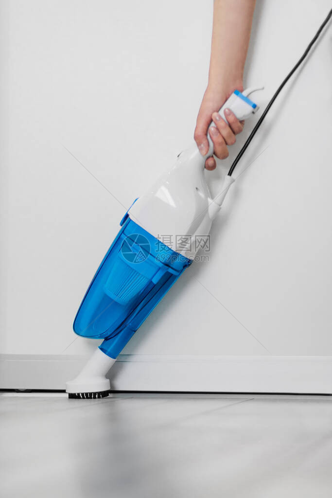 一名白衣女子用手持吸尘器清洁地板房子的一般清洁家庭主妇正在整理东图片