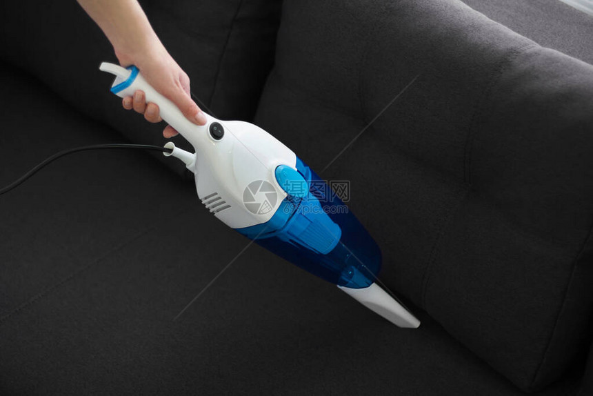 女人用手持吸尘器打扫沙发房子的一般清洁主妇正在整理东图片