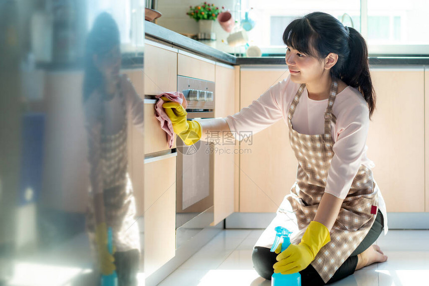 戴着橡胶防护手套的亚洲女在家中清洁厨房橱柜图片