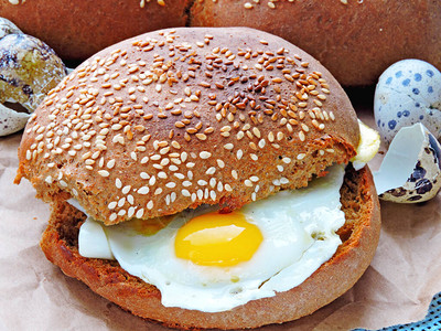 鹌鹑蛋汉堡鹌鹑蛋三明治黑麦面包配芝麻新鲜的热面包配煎鹌鹑蛋健图片