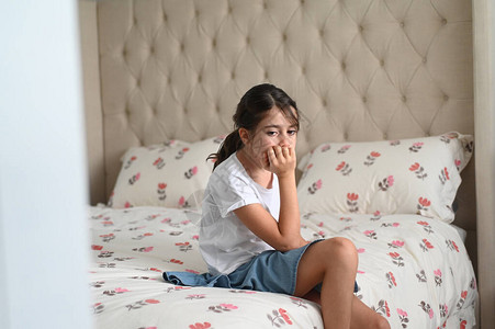 一位坐在床上的悲伤女孩10岁在卧室里焦虑不安真正的图片