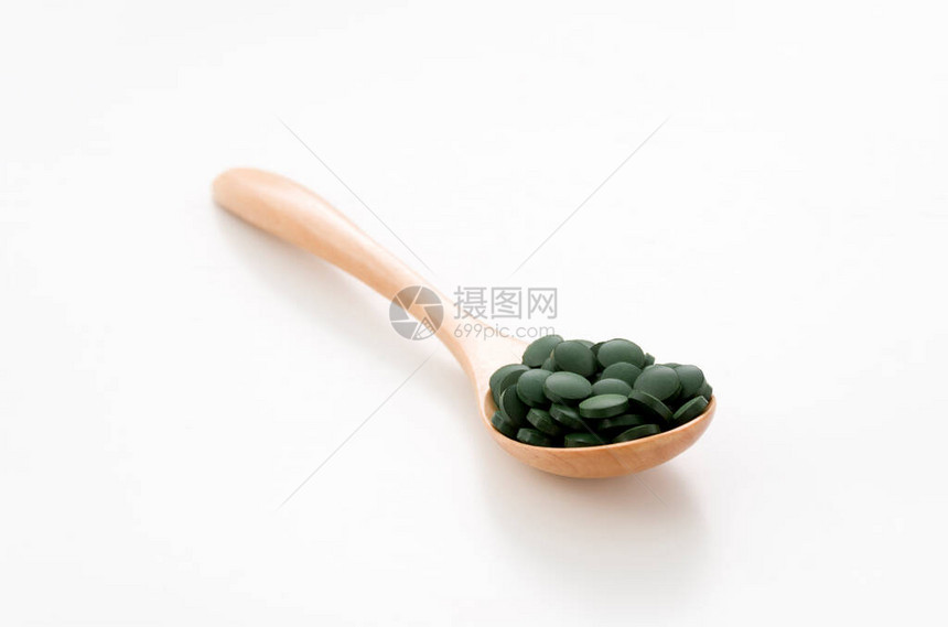绿药丸白底的木制勺子里的斯图片