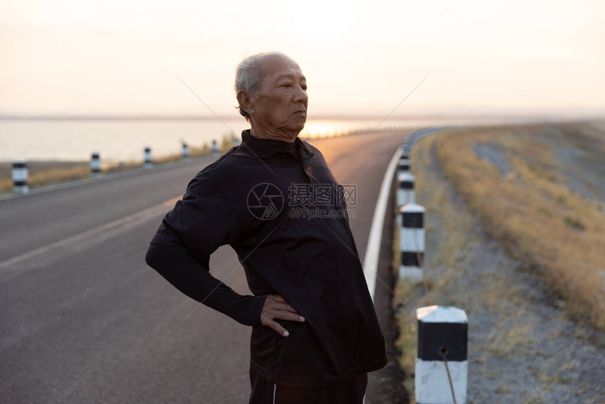 亚洲老年人运动老人热身扭腰或准备在早晨的阳光下在路上跑步锻炼健康生活方式和锻炼图片