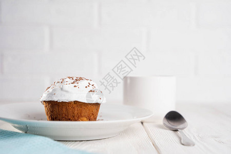 白色盘子上放着奶油和巧克力片的纸杯蛋糕图片