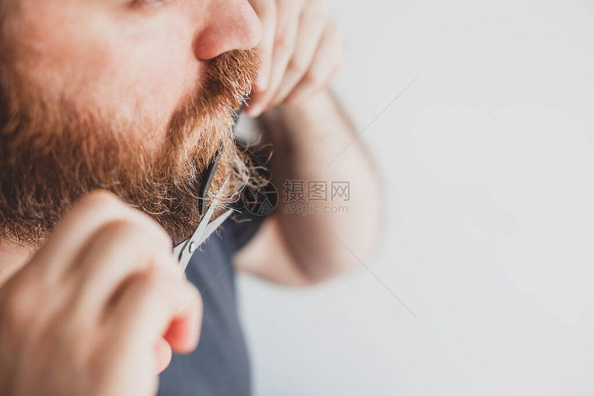 隔离期间的自我保健成年英俊的白种人男子在家里用剪刀亲自剪胡子和胡须冠状爆发和人们关闭图片