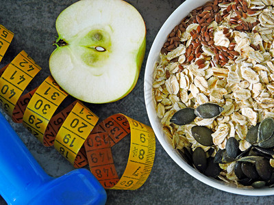 健身食品概念燕麦片水果坚果种子哑铃和卷尺健康和减肥概念的适图片