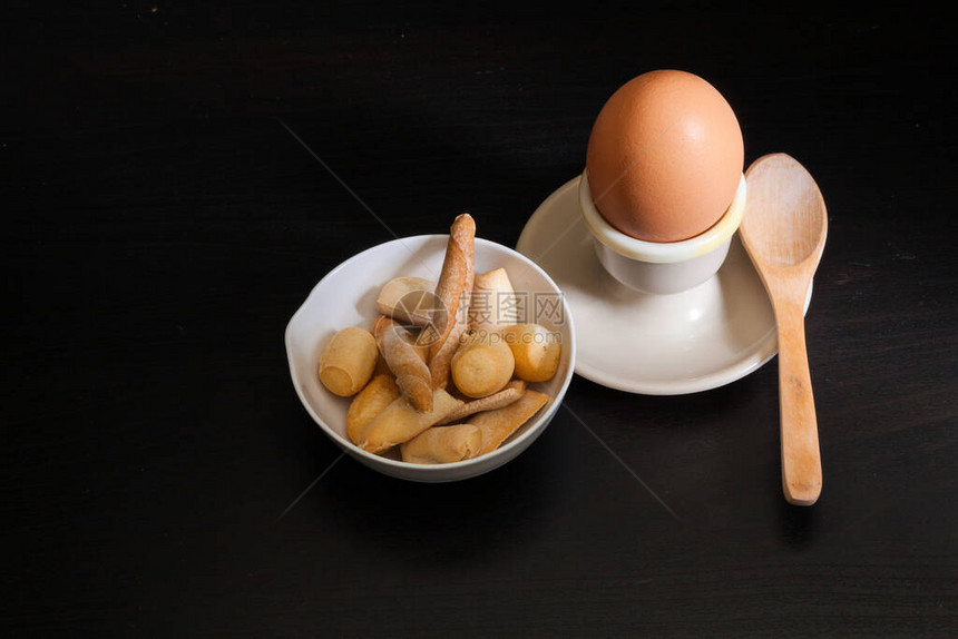 鸡蛋木勺和陶瓷碗中的软煮蛋图片