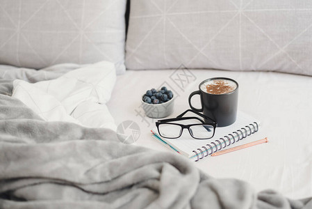早上在床上喝咖啡在家工作或学习咖啡蓝莓眼镜笔和记本图片