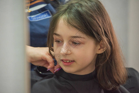 院概念小女孩在理发店剪刘海剪发9岁的女孩在一家美背景图片