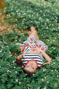 美丽的年轻女子闭着眼睛躺在森林色彩中图片