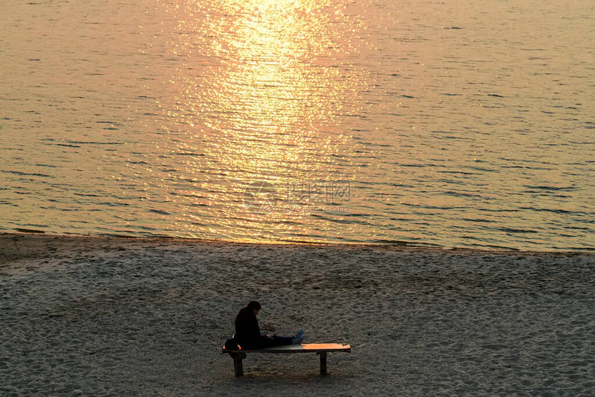 日落时坐在河岸上的人图片