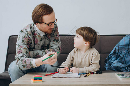 戴眼镜的红发父亲和蹒跚学步的儿子一起画彩色铅笔图片