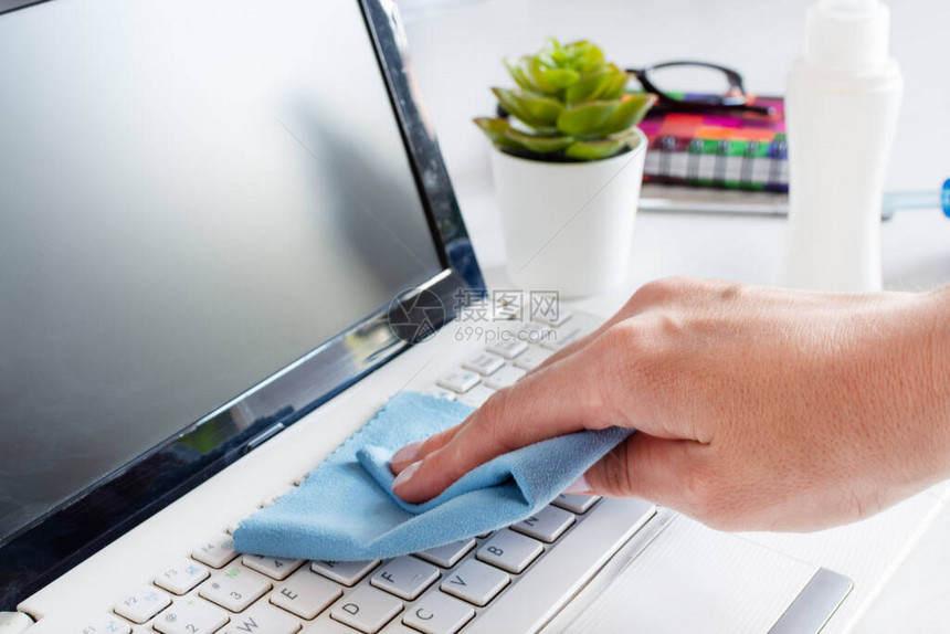 妇女用抗菌布对计算机键盘进行手消毒图片