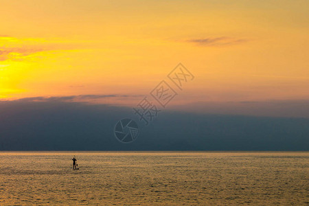 日落时在海中划桨的剪影的女人图片