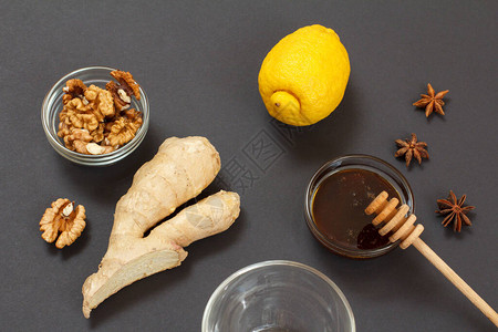 使用柠檬姜汁蜂蜜和核桃在黑色背景中提供冷冻和流感的卫生救济食品图片