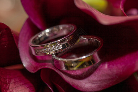 关闭两个结婚戒指和婚礼花束图片