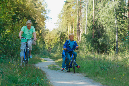 活跃的老奶带着孩子在大自然中骑自行图片